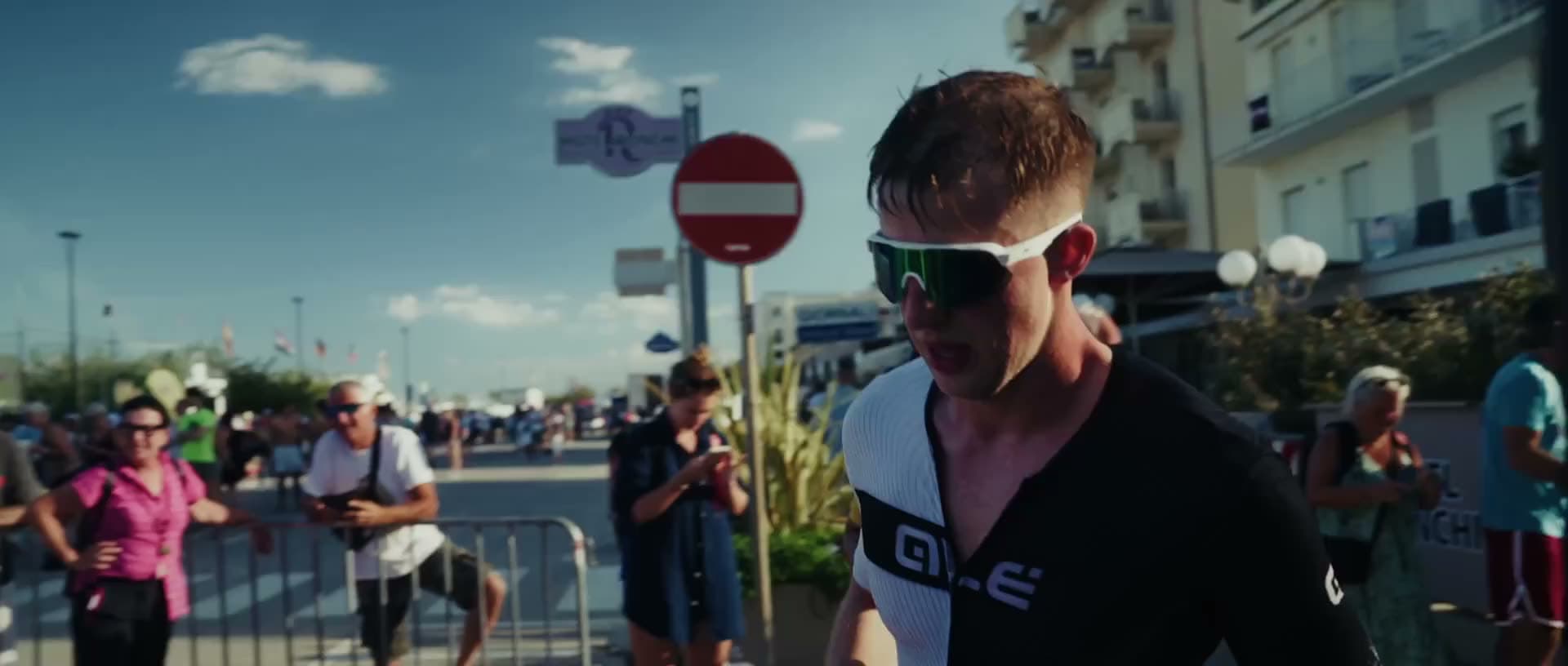 Závodník v plném nasazení na trati, kolem fandí diváci.
